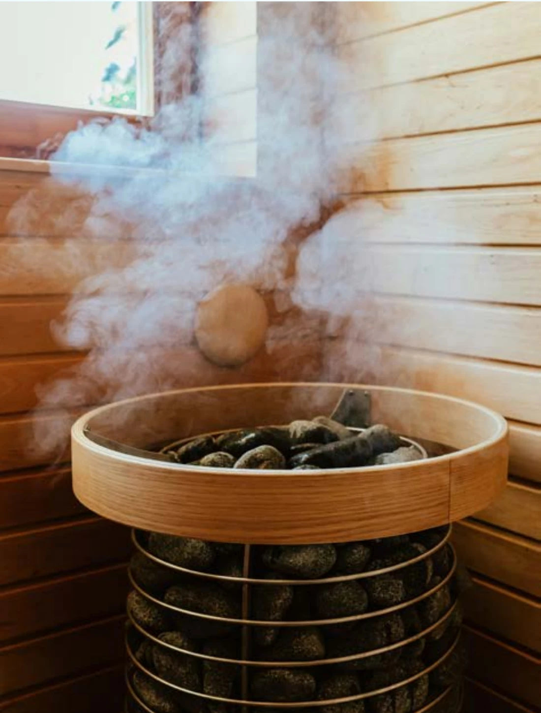 Traditionelle Sauna mit Ofen, Saunasteinen und Aufgussdampf